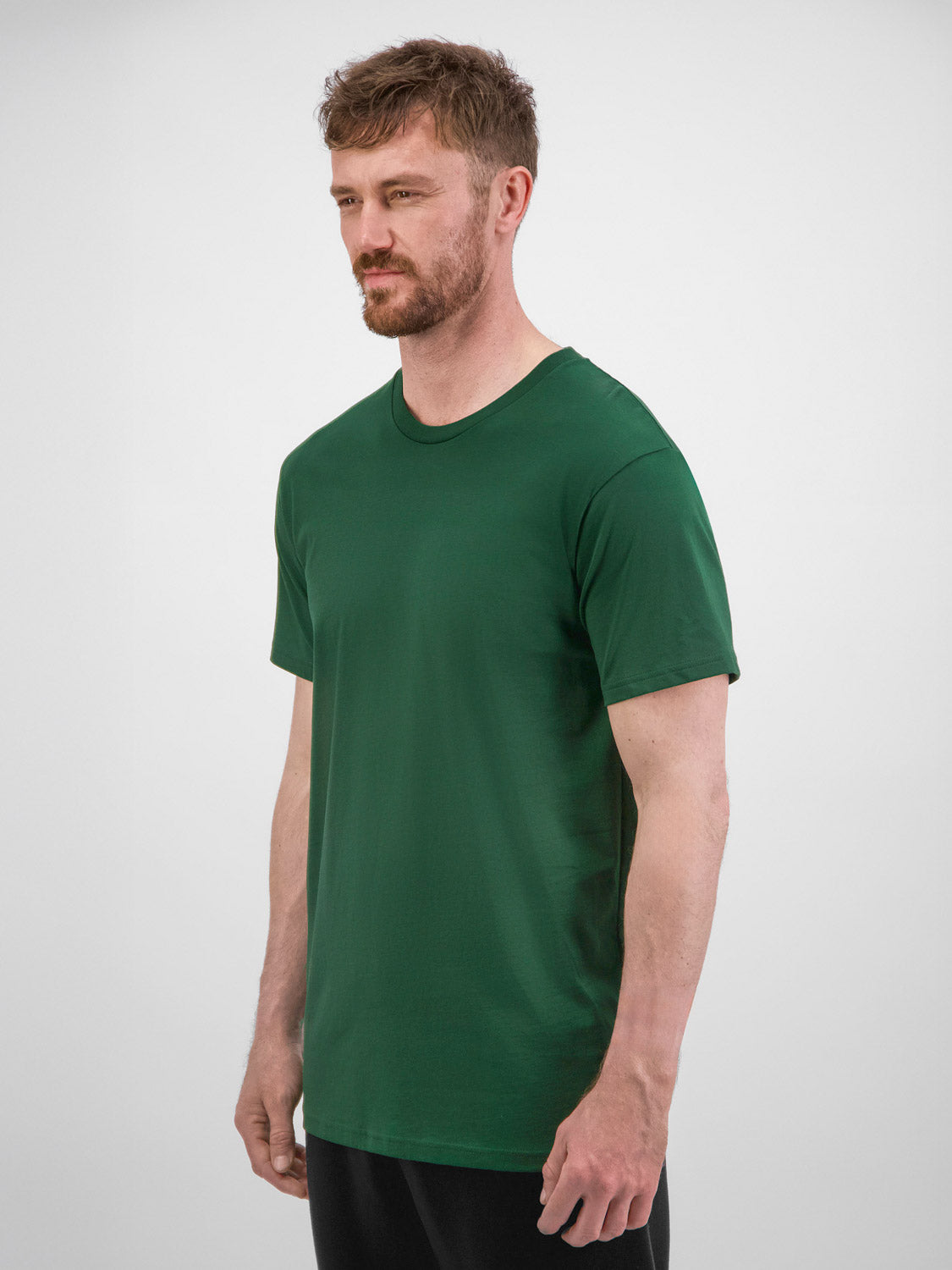 A man wearing a dark green, short-sleeve cotton crew neck t-shirt against a white background.