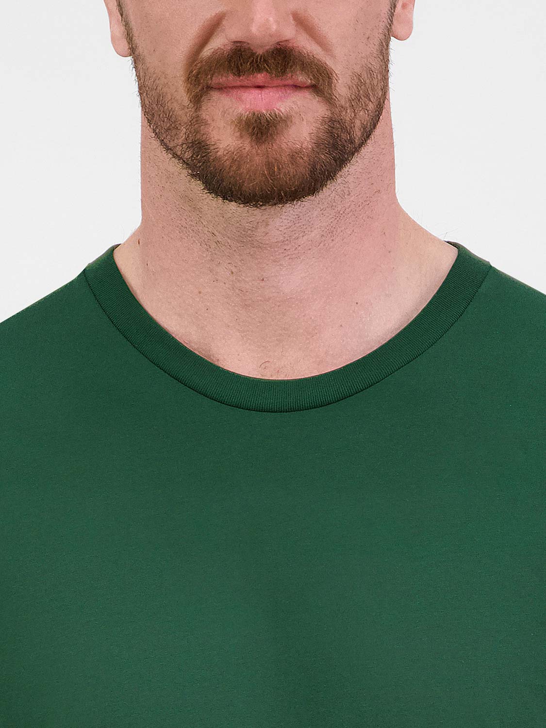 Close-up of a man wearing a dark green Mens Basis Short Sleeve Tee with a ribbed crew neckline.