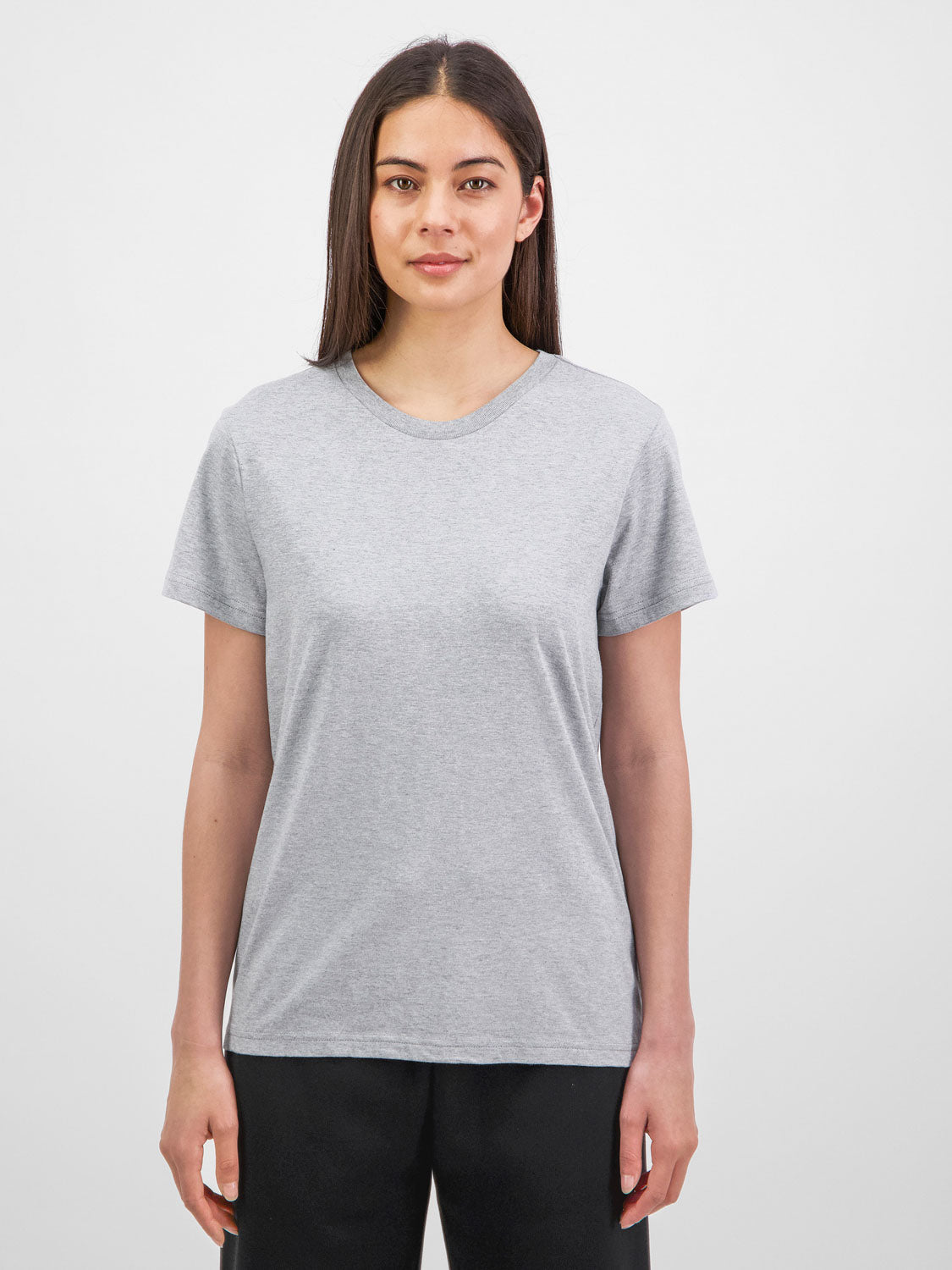 A woman wearing a grey short sleeve crew neck t-shirt and black pants.