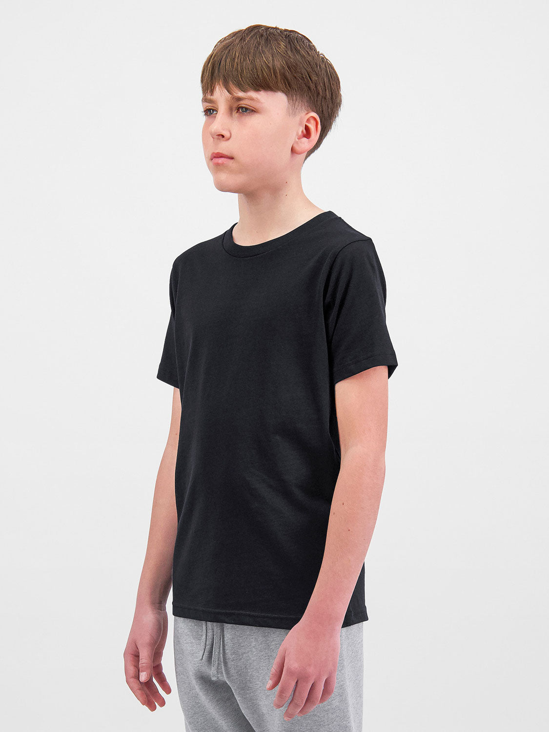 A young person wearing a black short sleeve cotton crew neck t-shirt and grey sweatpants.