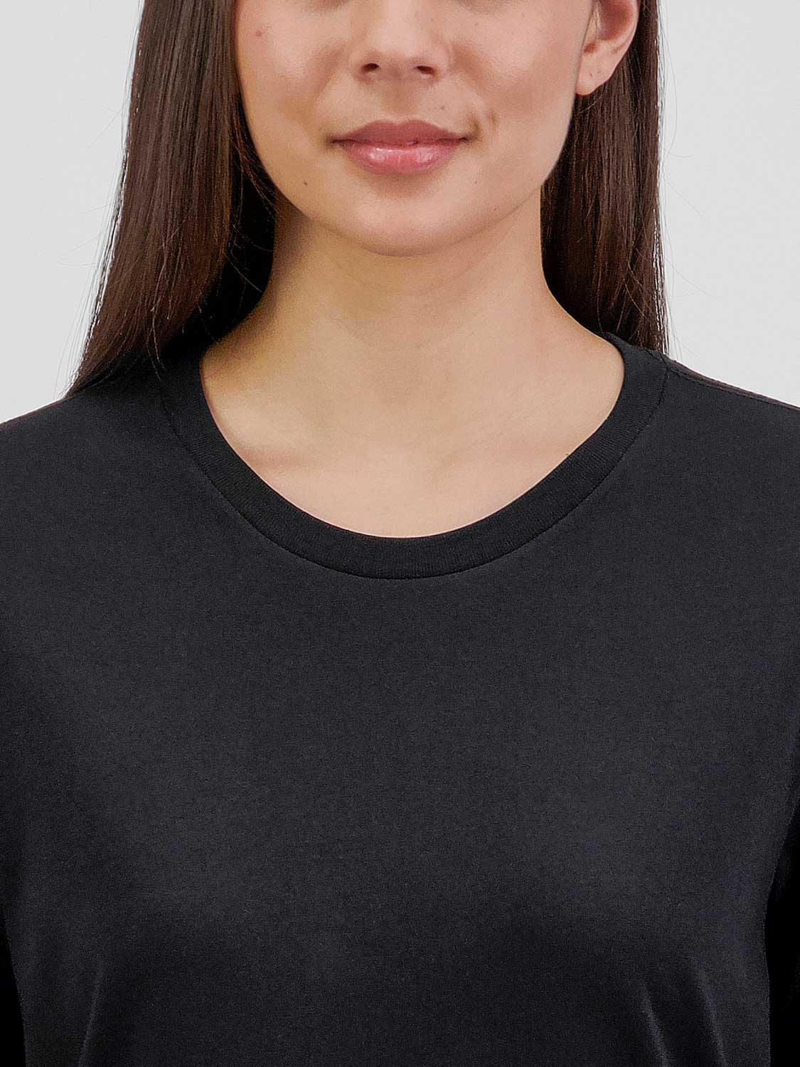 Close-up of a woman wearing a black long sleeve cotton tee with a ribbed crew neck.