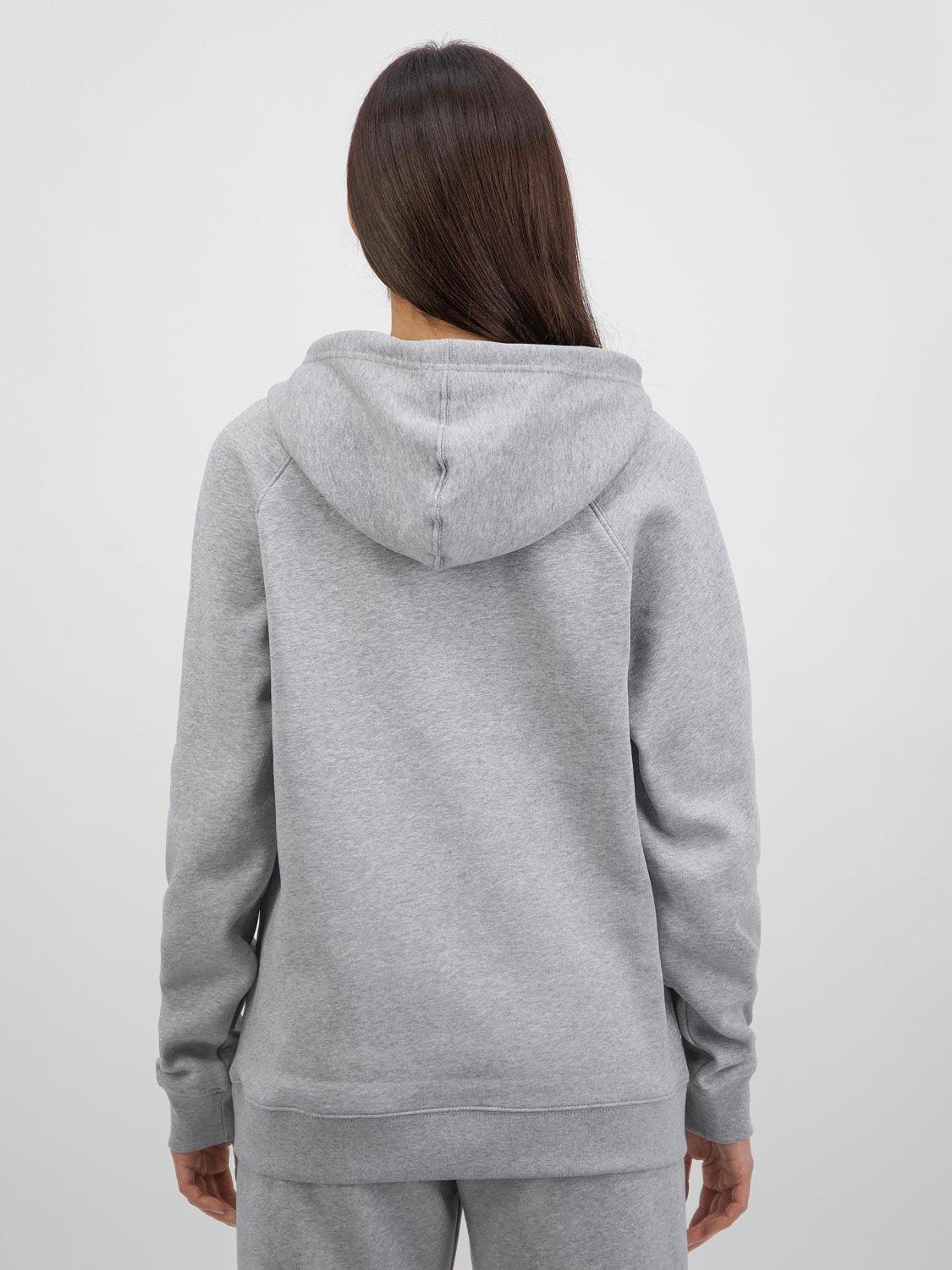 Rear view of a woman wearing a grey marle Basis Hoodie with a relaxed fit and ribbed hem.