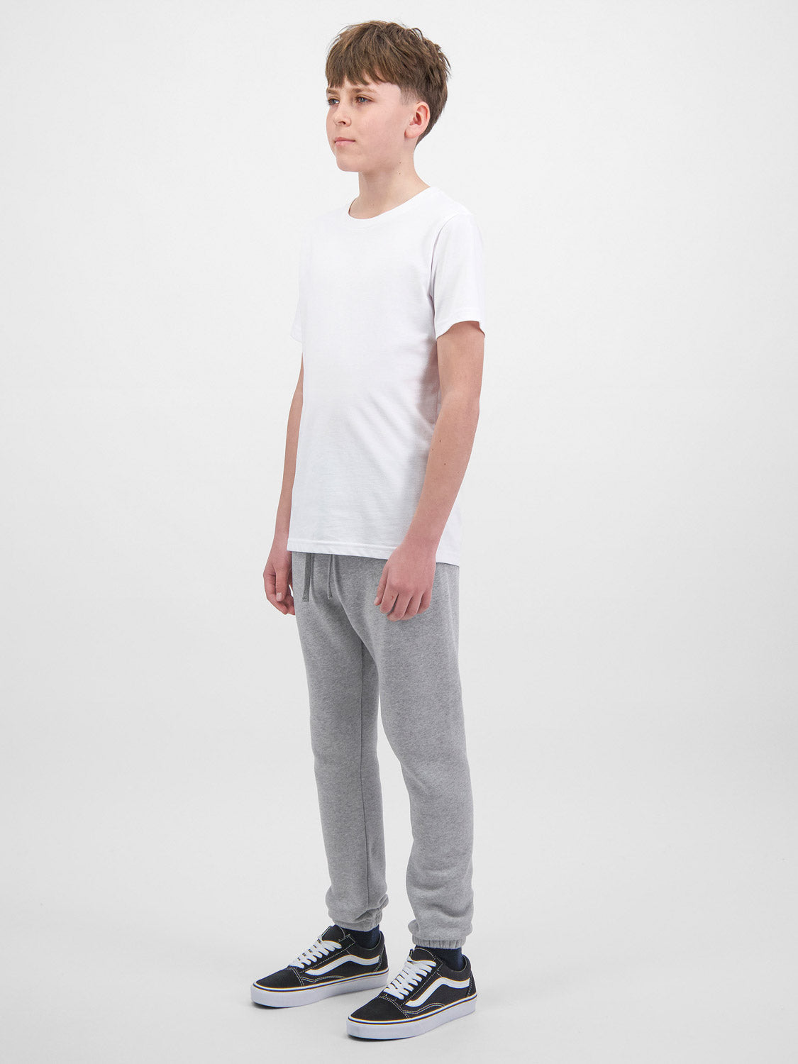A youth model wears grey fleece track pants with an elastic drawstring waist and cuffed ankles.