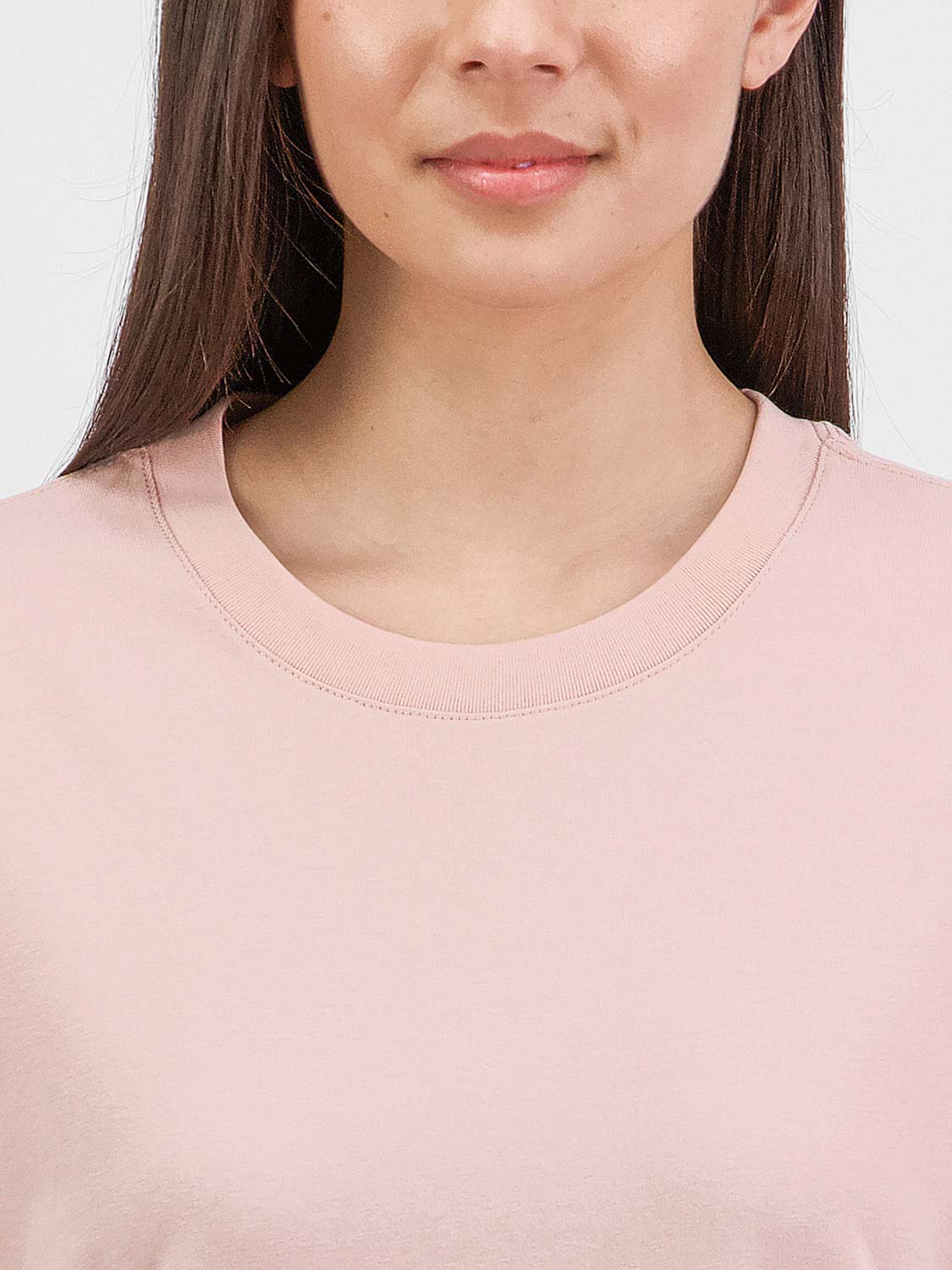 Close-up of a woman wearing a light pink short sleeve tee with a ribbed crew neckline.