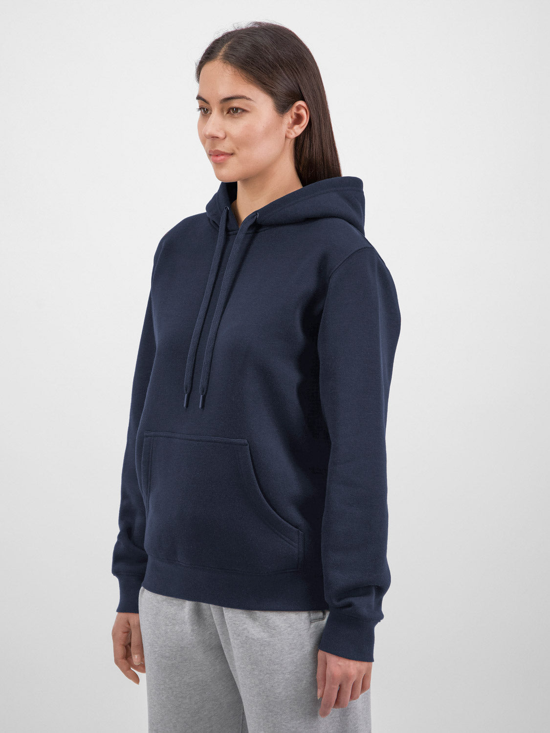 A woman wearing a navy blue mid-weight everyday hoodie with a front pocket and drawstring hood.