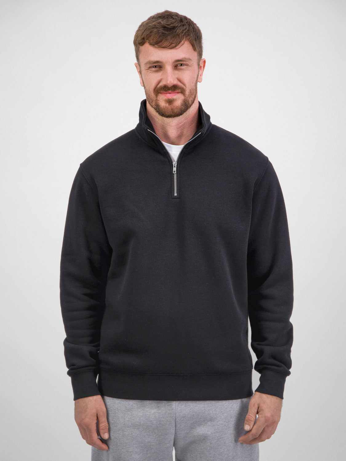A man wearing a black quarter-zip fleece sweatshirt with ribbed cuffs and a stand-up collar.