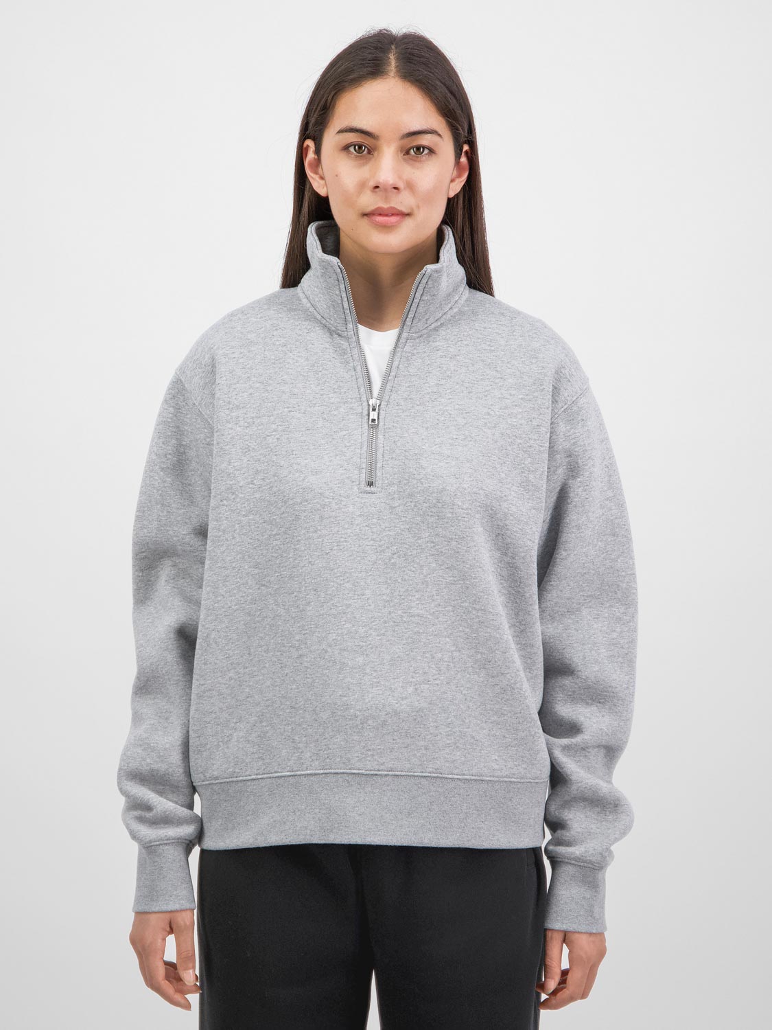 A woman wearing a grey quarter-zip sweatshirt with a relaxed fit and ribbed cuffs.