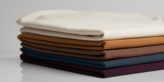 Stack of folded fabric swatches in various colors on a light gray background