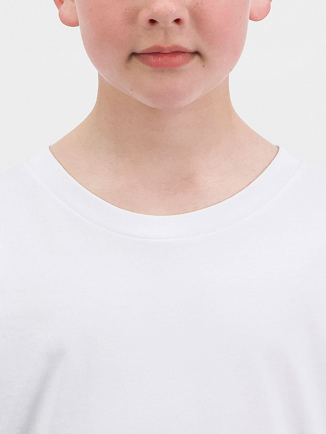 Close-up of a child wearing a white long-sleeve cotton tee with a ribbed crew neckline.