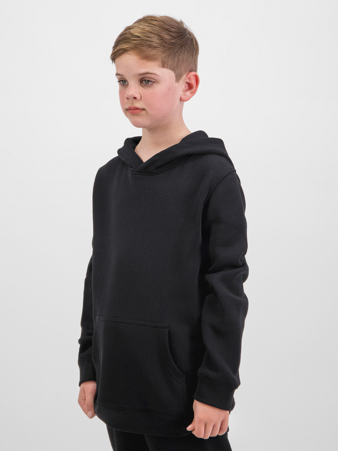 A young boy wearing a classic black kids' hoodie with a front kangaroo pocket and ribbed cuffs.