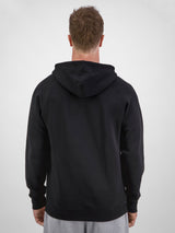 Rear view of a man wearing a black Basis Hoodie with raglan sleeves and a hood.