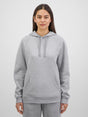 A woman wearing a light grey marle raglan sleeve hoodie with a front kangaroo pocket.