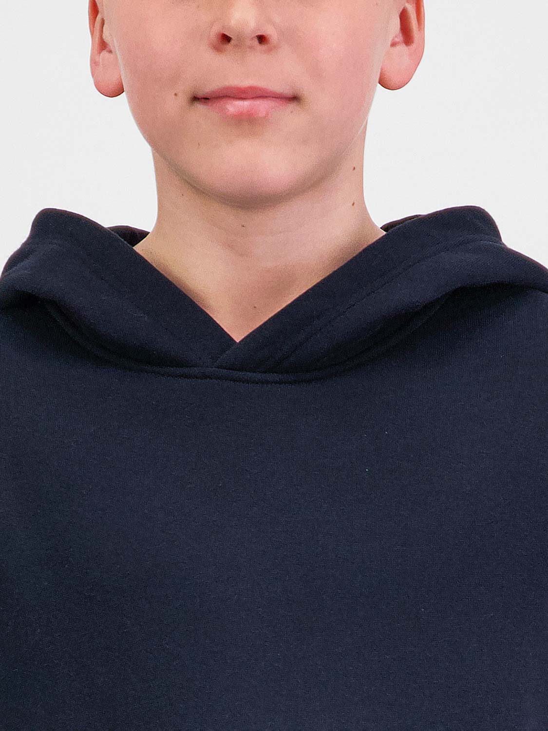 Close-up of a child wearing a navy blue Youth Basis Hoodie with a crossover hood design.