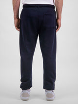 Rear view of a man wearing navy blue Basis Track Pants with a back pocket and elasticated cuffs.