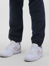 A person wearing navy blue Mens Basis Track Pants with elasticated ankle cuffs and white sneakers.