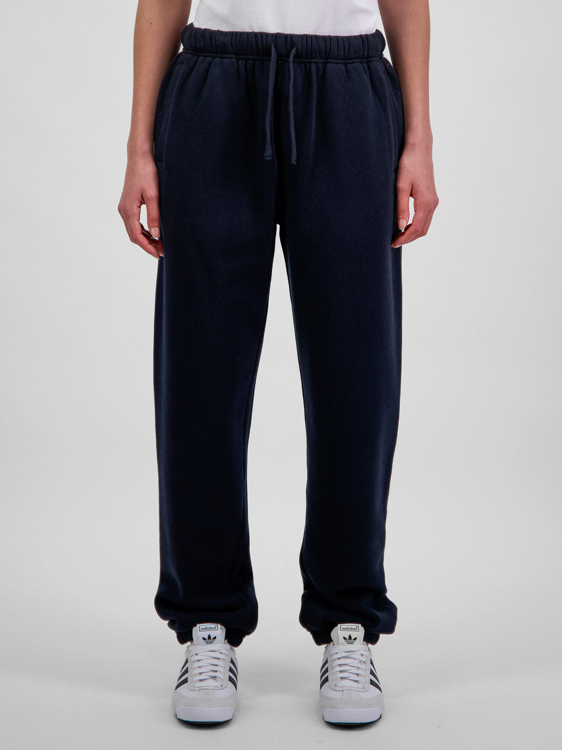 A person wearing navy blue relaxed-fit fleece track pants with an elastic drawstring waistband.