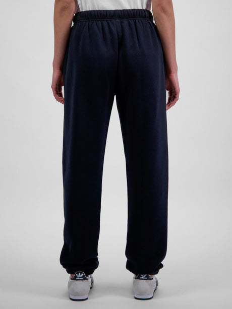 Rear view of a person wearing navy blue relaxed-fit fleece track pants with elastic cuffs.