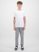 A young person wearing grey Youth Basis Track Pants with an elastic waist and cuffed ankles.