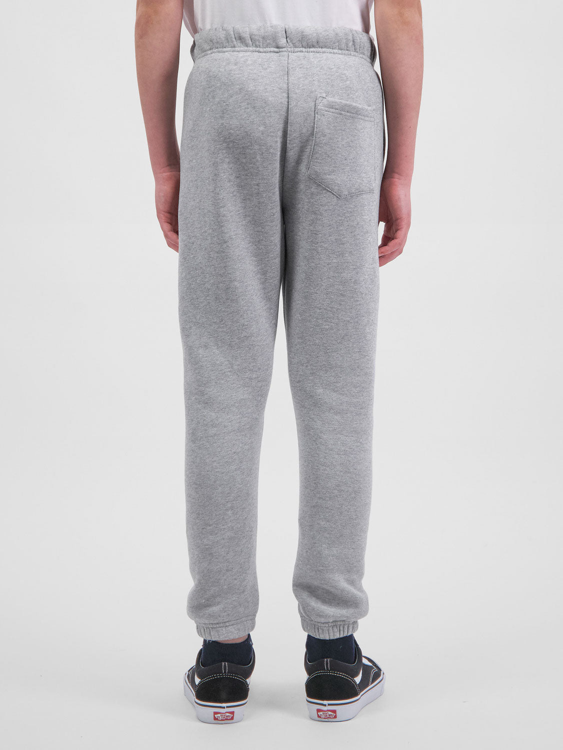 Rear view of a person wearing grey youth track pants with an elastic waist and cuffed ankles.