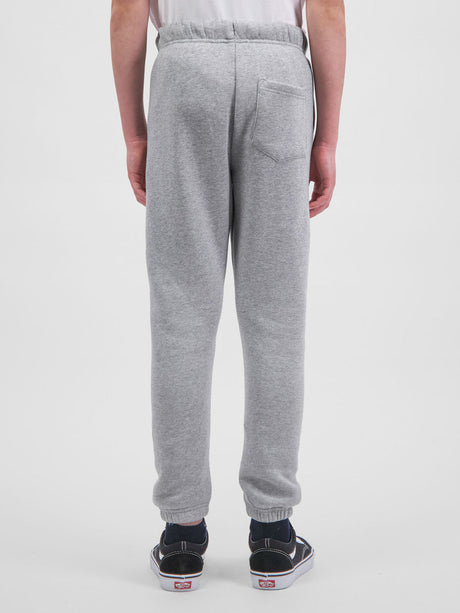Rear view of a person wearing grey youth track pants with an elastic waist and cuffed ankles.
