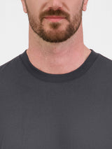 Close-up of a man wearing a charcoal grey short sleeve tee with a ribbed crew neckline.
