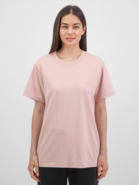 A woman wearing a relaxed-fit, light pink short sleeve crew neck t-shirt.
