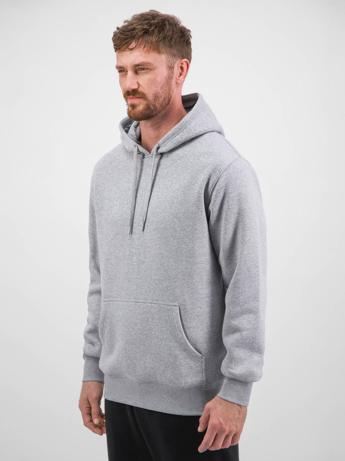 A man wearing a light grey heathered everyday hoodie with a front kangaroo pocket and drawstrings.