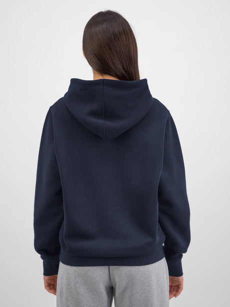 Rear view of a woman wearing a navy blue hooded sweatshirt and grey sweatpants.
