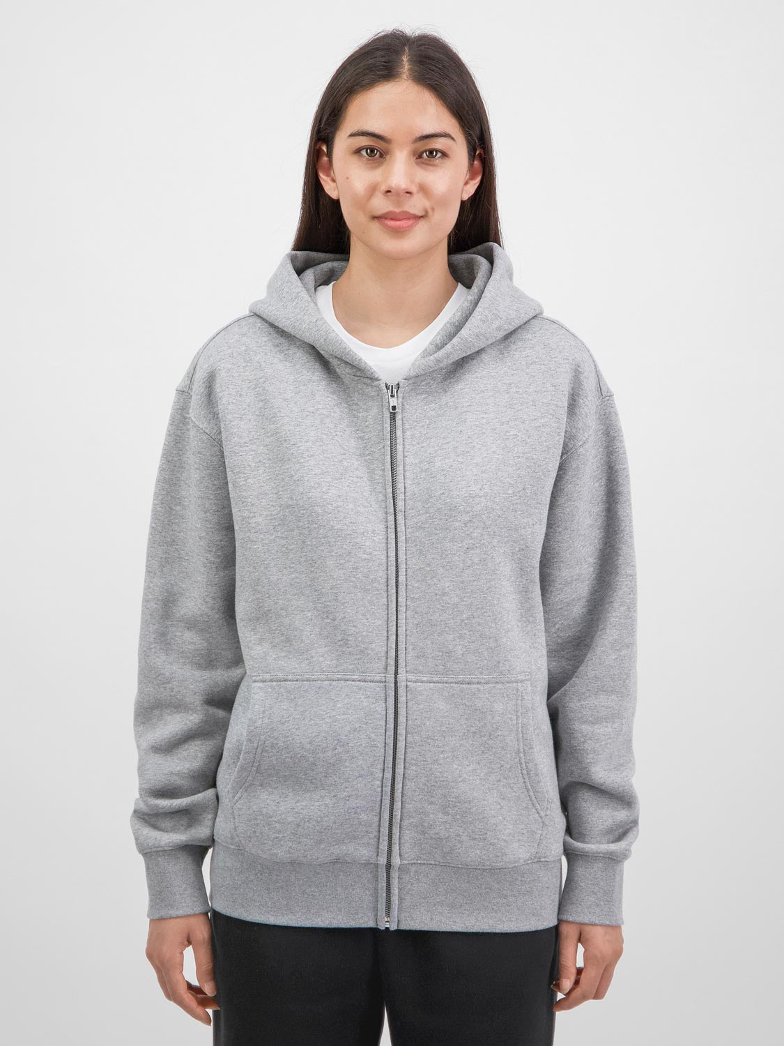 A woman wearing a grey Everyday Zip Hoodie with a relaxed fit and front pockets.