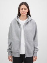 A woman wears a relaxed-fit grey zip-up hoodie with front pockets and a white t-shirt.