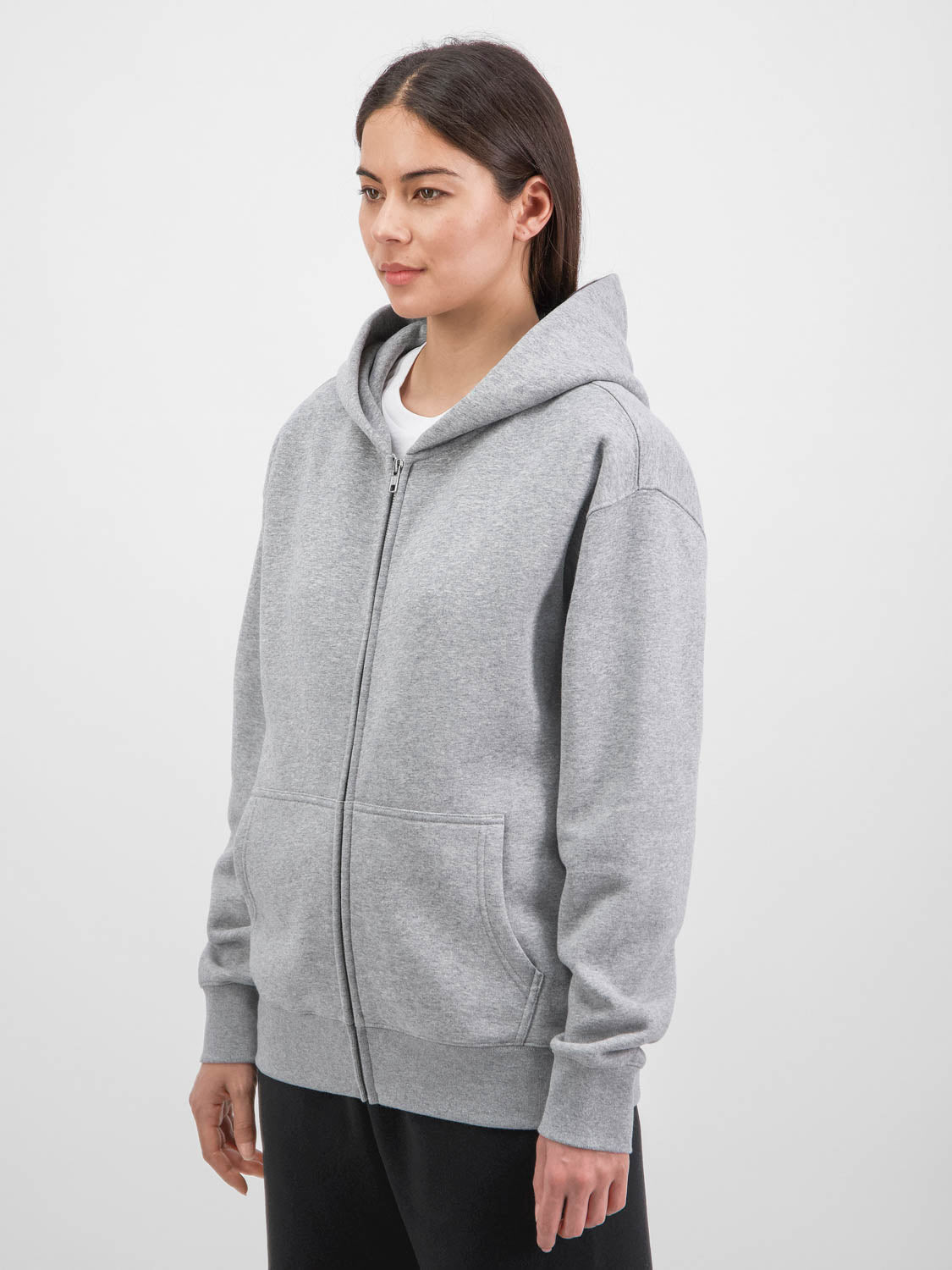 A woman wearing a grey zip-up hoodie with a relaxed fit, front pockets, and ribbed cuffs.
