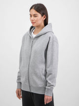 A woman wearing a grey zip-up hoodie with a relaxed fit, front pockets, and ribbed cuffs.