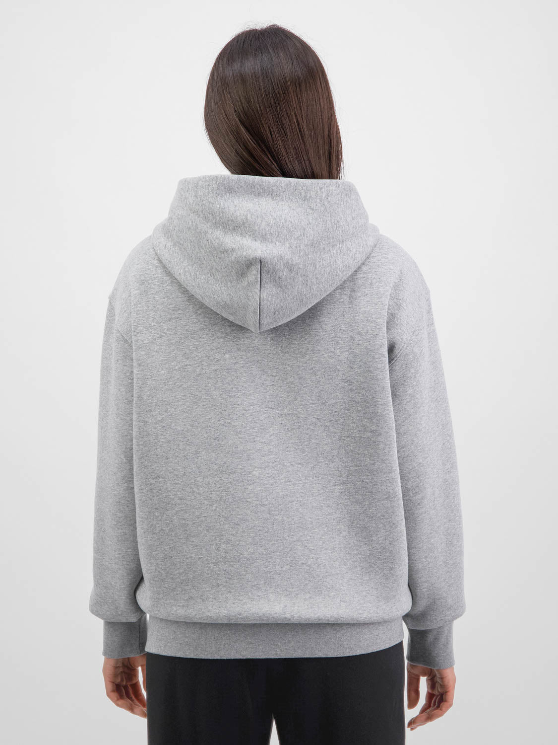 Rear view of a woman wearing a relaxed-fit grey zip-up hoodie with a hood and ribbed cuffs.