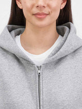 Close-up of a woman wearing a grey zip-up hoodie over a white t-shirt.