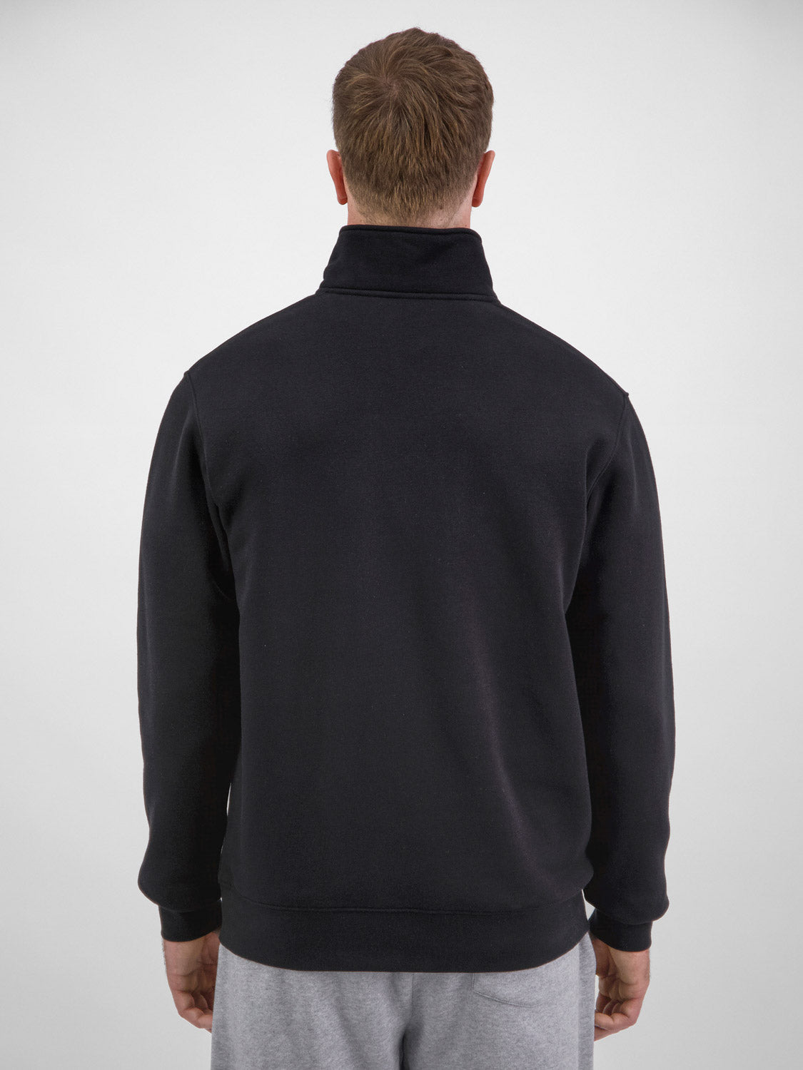 Rear view of a man wearing a black quarter-zip fleece sweatshirt with ribbed cuffs and hem.
