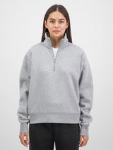 A woman wearing a grey quarter-zip sweatshirt with a relaxed fit and ribbed cuffs.
