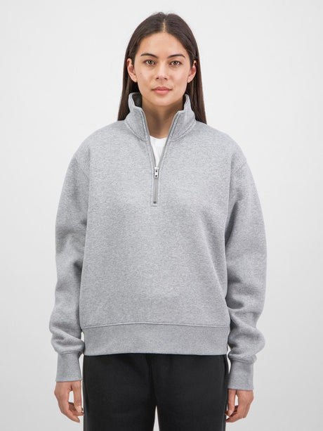 A woman wearing a grey quarter-zip sweatshirt with a relaxed fit and ribbed cuffs.