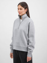 A woman wearing a grey quarter-zip sweatshirt with a relaxed fit and ribbed cuffs.