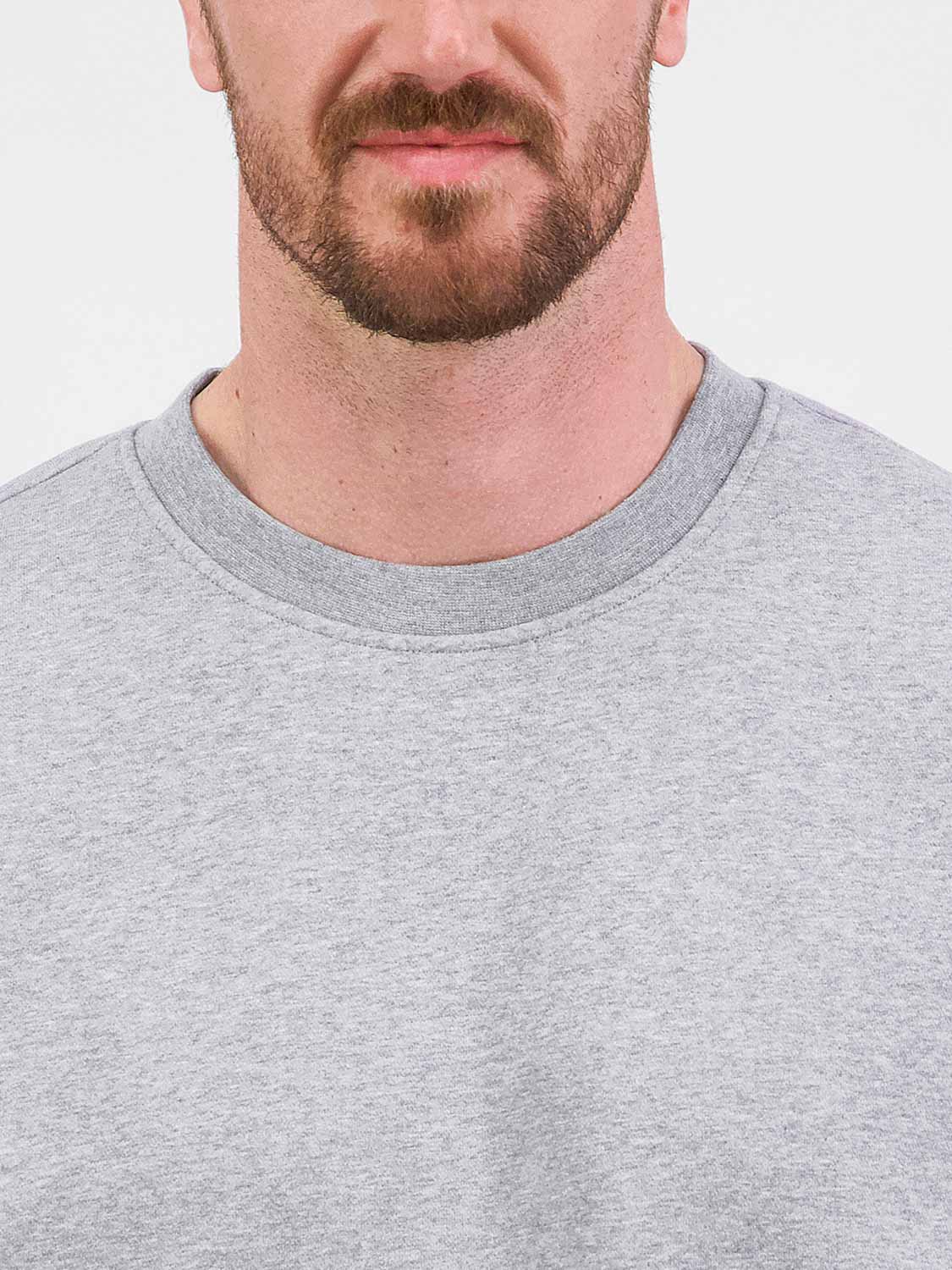 Close-up of a man wearing a grey crew neck sweatshirt with a ribbed collar.