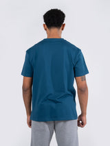 Ramo - Rear view of a man wearing a teal short-sleeve cotton t-shirt and grey shorts.